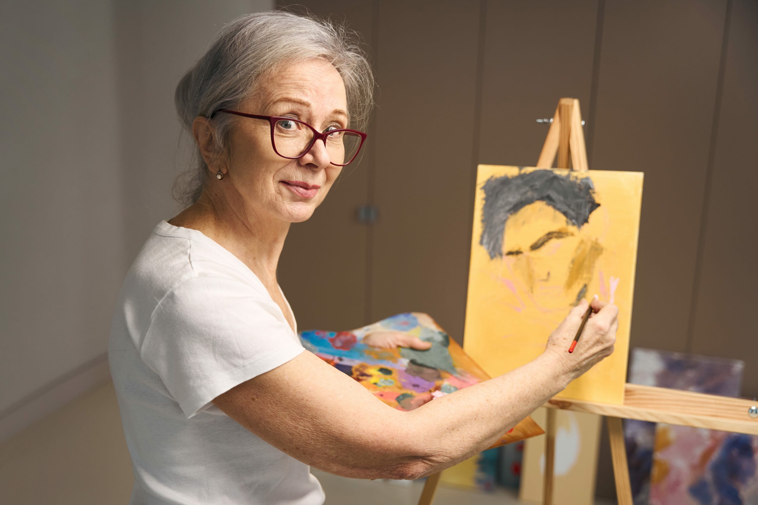 talented-elderly-woman-stands-at-an-easel-with-a-p-2023-11-27-05-32-38-utc-min