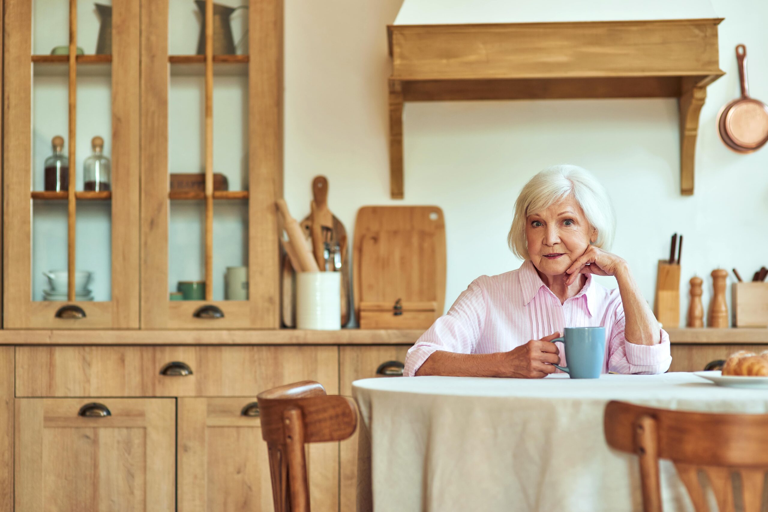 cheerful-elderly-woman-with-cup-of-hot-drink-sitti-2023-11-27-05-01-43-utc-min